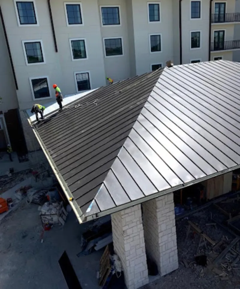 Crew installing standing seam metal roof panels on a commercial project in Pukalani